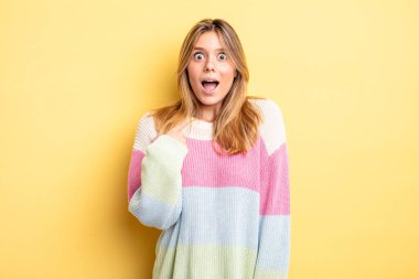 Şok olmuş ve ağzı açık, kendini işaret eden sarışın güzel bir kadın.