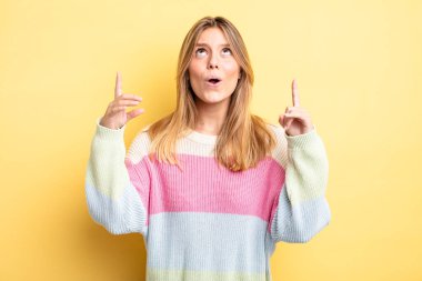 Sarışın, güzel bir kadın. Korkmuş ve ağzı açık. Şok olmuş ve şaşırmış bir şekilde yukarı bakıyor.