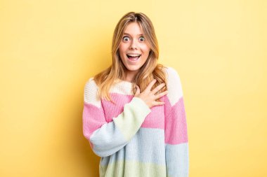 Sarışın, güzel bir kadın şaşkın ve şaşırmış hissediyor, gülümsüyor, el ele tutuşuyor, o olmaktan mutlu ya da minnettarlık gösteriyor.