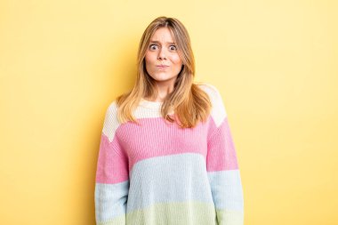 Sarışın, güzel bir kadın. Kafası karışık ve kuşkulu. Merak ediyor ya da karar vermeye çalışıyor.