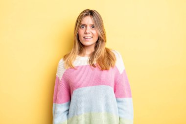 blonde pretty woman feeling puzzled and confused, with a dumb, stunned expression looking at something unexpected