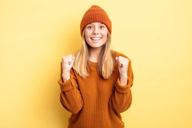 Güzel sarışın kadın zaferle bağırıyor, gülüyor, mutlu ve heyecanlı hissediyor başarıyı kutlarken.