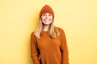 Sarışın, güzel bir kadın neşeli ve tesadüfen gülümsüyor pozitif, mutlu, kendinden emin ve rahat bir ifadeyle.