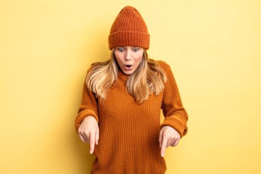 Sarışın, güzel bir kadın şoke olmuş, ağzı açık ve şaşkın, inançsızlık ve şaşkınlık içinde bakıyor ve onu işaret ediyor.