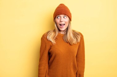 Sarışın, güzel bir kadın şaşkın, mutlu, şaşkın ve şaşırmış hissediyor, ağzı açık bir şekilde yana bakıyor.