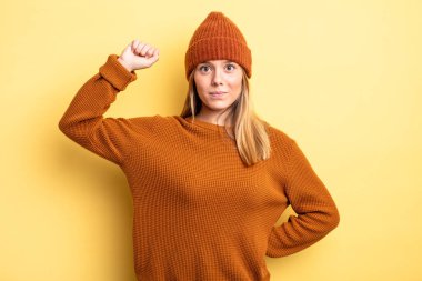 Sarışın, güzel bir kadın ciddi, güçlü ve asi hissediyor, yumruğunu kaldırıyor, protesto ediyor ya da devrim için savaşıyor.