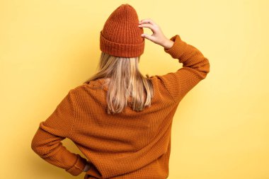 Sarışın, güzel bir kadın bilgisiz ve kafası karışık, bir çözüm düşünüyor, eli kalçasında, diğeri kafasında, dikiz aynasından.