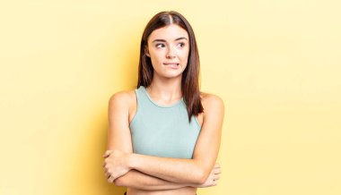 Hispanik güzel kadın şüpheye düşüyor ya da düşünüyor, dudağını ısırıyor ve kendini güvensiz ve gergin hissediyor, kenarda yer arıyor.