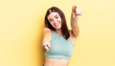 İspanyol güzel kadın mutlu ve kendinden emin, kamerayı iki eliyle gösteriyor ve gülüyor, seni seçiyor.