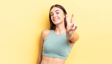 İspanyol güzel kadın gülümsüyor ve mutlu görünüyor, kaygısız ve olumlu, zafer ya da barış işareti yapıyor.