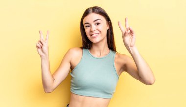 İspanyol güzel kadın gülümsüyor ve mutlu görünüyor, arkadaş canlısı ve tatmin olmuş, zafer ya da barış işareti yapıyor.