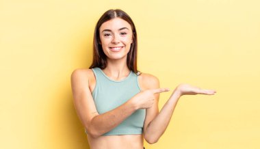 İspanyol güzel kadın gülümsüyor, mutlu, kaygısız ve tatmin olmuş hissediyor, fotokopi alanındaki konsepte ya da fikre işaret ediyor.