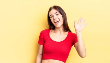 İspanyol güzel kadın mutlu ve neşeyle gülümsüyor, el sallıyor, seni selamlıyor ya da veda ediyor.