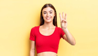 İspanyol güzel kadın gülümsüyor ve arkadaş canlısı görünüyor. Üç ya da üç numarayı gösteriyor. Elleri önde, geriye doğru sayıyor.