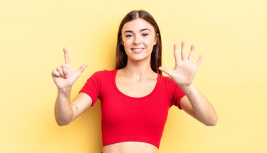 İspanyol güzel kadın gülümsüyor ve arkadaş canlısı görünüyor, 7 ya da 7 numarayı gösteriyor, eli önde, geriye doğru sayıyor.