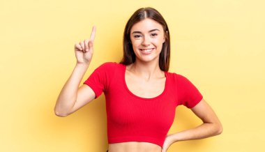 İspanyol güzel kadın neşeyle ve mutlu bir şekilde gülümsüyor, tek eliyle boşluğu dolduruyor.