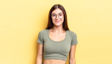 İspanyol güzel kadın pozitif ve kendinden emin gülümsüyor. Tatmin olmuş, arkadaş canlısı ve mutlu görünüyor.