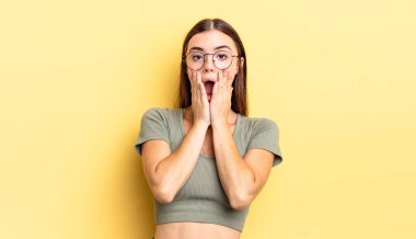 İspanyol güzel kadın şok olmuş ve korkmuş hissediyor, ağzı açık ve elleri yanaklarında korkmuş görünüyor.