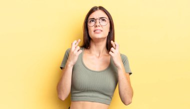 İspanyol güzel kadın endişeyle dua ediyor ve endişeli bir bakışla iyi şanslar diliyor.