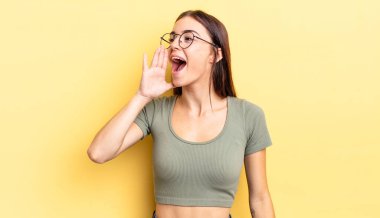 Latin kökenli güzel bir kadın öfkeyle ve yüksek sesle bağırıyor. Yan taraftaki boşluğu kopyalasın, eli ağzının yanında.