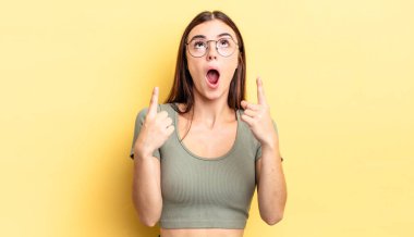 Hispanik güzel kadın şaşkınlık içinde ve ağzı açık. Şok olmuş ve şaşırmış bir bakışla yukarı bakıyor.