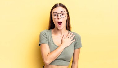 İspanyol güzel kadın şaşkın ve şaşırmış hissediyor, gülümsüyor, el ele tutuşuyor, mutlu ya da minnettarlık gösteriyor.