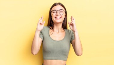 İspanyol güzel kadın gülümsüyor ve endişeyle iki parmağını çapraz yapıyor. Endişeli hissediyor, iyi şanslar diliyor ya da umut ediyor.