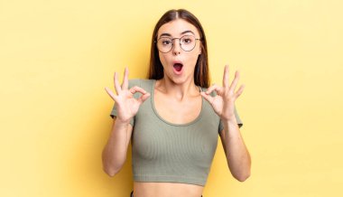 İspanyol güzel kadın şok olmuş, şaşırmış ve şaşırmış hissediyor. Onaylıyor. İki eliyle işaret veriyor.