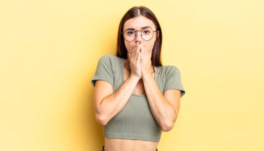 Hispanik güzel kadın endişeli, üzgün ve korkmuş hissediyor, elleriyle ağzını kapatıyor, endişeli ve berbat görünüyor.