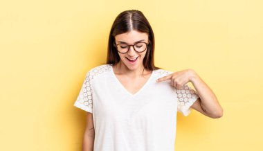 İspanyol güzel kadın neşeyle gülümsüyor, yere bakıyor ve göğsüne işaret ediyor.