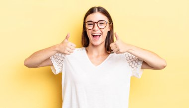 İspanyol güzel kadın gülümsüyor mutlu, pozitif, kendinden emin ve başarılı, her iki başparmağıyla