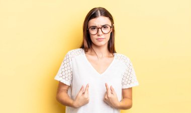 İspanyol asıllı güzel bir kadın, şaşkın ve şaşkın bir bakışla kendini işaret ediyor. Seçildiğine şaşırmış ve şaşırmış.