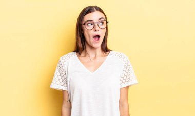 İspanyol güzel kadın şaşkın, mutlu, şaşkın ve şaşırmış hissediyor, ağzı açık bir şekilde yana bakıyor.