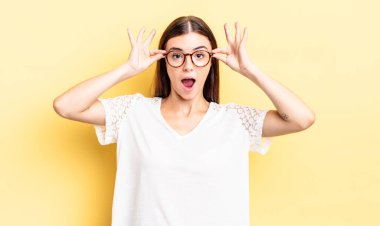 İspanyol güzel kadın şaşkın, şaşkın ve şaşırmış hissediyor, elinde şaşkın, inançsız bir bakışla gözlük tutuyor.