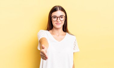 İspanyol güzel kadın gülümsüyor, mutlu görünüyor, kendinden emin ve arkadaş canlısı, bir anlaşmaya varmak için el sıkışıyor, işbirliği yapıyor.