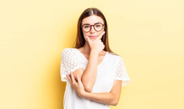 İspanyol güzel kadın ciddi, düşünceli ve güvensiz görünüyor, bir kolu çapraz ve çene üzerinde, seçenekleri tartıyor