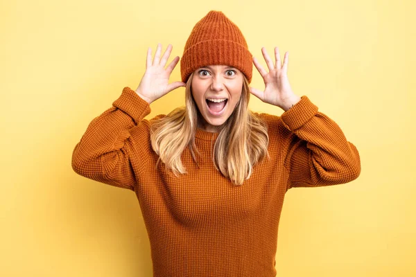 Sarışın, güzel bir kadın panik ya da öfke içinde bağırıyor, şok olmuş, korkmuş ya da öfkeli, elleri başının yanında.