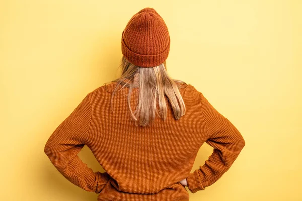 Sarışın, güzel bir kadın kafası karışık ya da dolgun ya da şüphe ve soru dolu, merak ediyor, elleri kalçasında, dikiz aynasından.