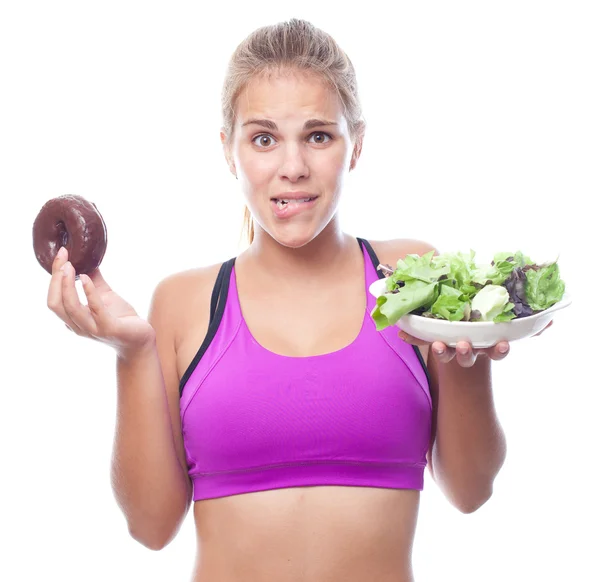 Young cool woman doubting with a donut and salad — Stock Photo, Image