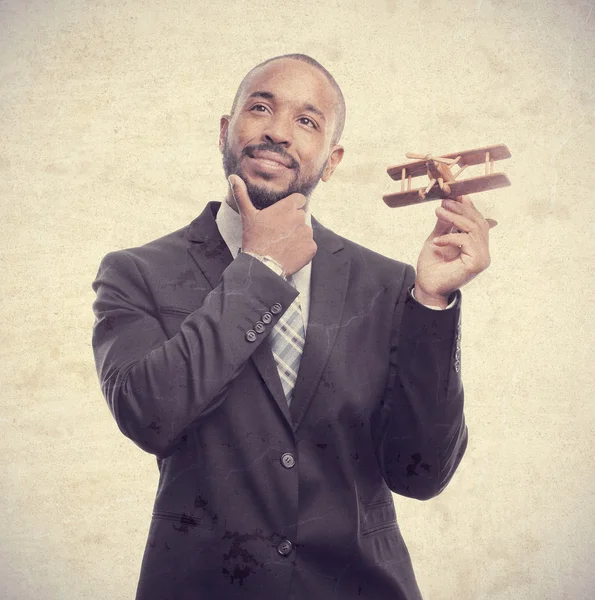 Młode fajne czarny człowiek myśli z drewniany samolot — Zdjęcie stockowe