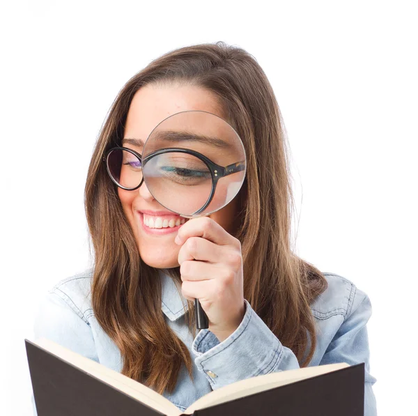 Jovem mulher olhando para o livro por lupa — Fotografia de Stock