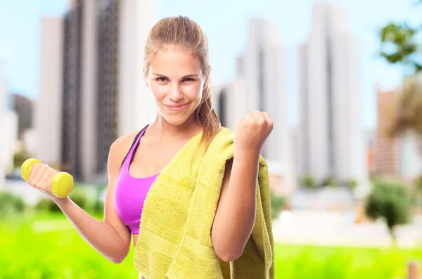 Young cool woman with dumbbell and a towel — Stock Photo, Image