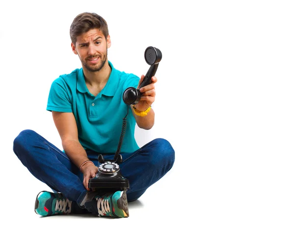 Killen sitter och håller en telefon — Stockfoto