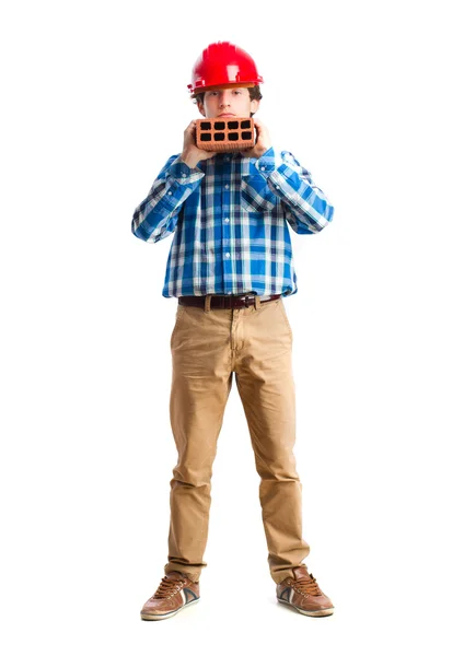 Adolescente com capacete de trabalho segurando um tijolo — Fotografia de Stock