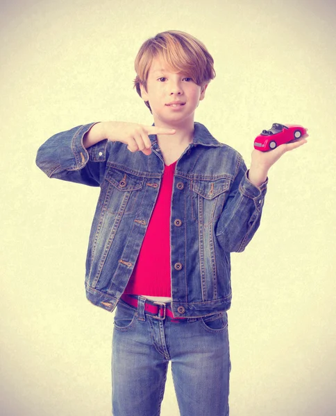 Forvirret dreng peger på en legetøjsbil - Stock-foto