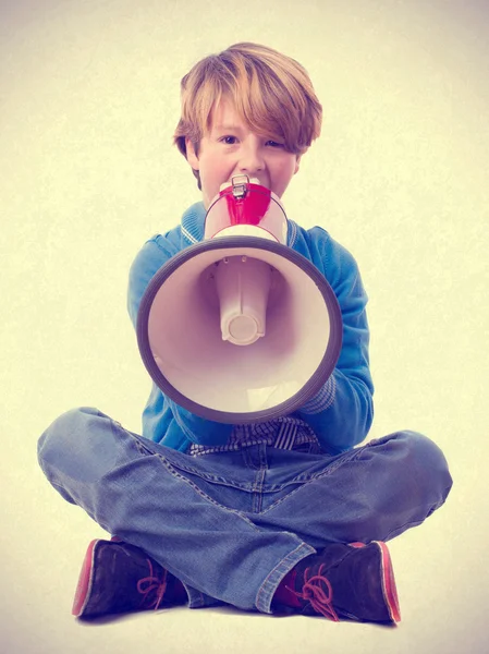 Мальчик сидит и кричит рядом с мегафоном — стоковое фото