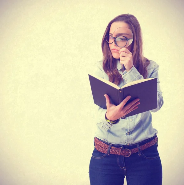 Jonge vrouw kijken naar boek door vergrootglas — Stockfoto