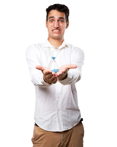 Worried young man with sand timer — Stock Photo, Image