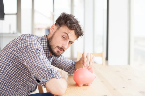 Junger Mann mit Sparschwein — Stockfoto