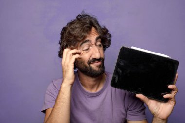 Genç, sakallı, dokunmatik ekranı tutan bir adam.